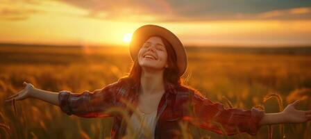 Backlit young woman smile with open arms and closed eyes wearing round hat enjoys a beautiful moment life on the fields at sunset photo