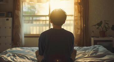 espalda ver de joven hombre meditando en el cama en el Mañana foto