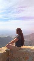 contento asiático mujer turista aumento manos disfruta respiración Fresco aire alto en nublado montañas a frío clima. joven caminante a increíble brumoso antecedentes de montaña paisaje en pie atrás. activo deporte. video