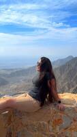 Happy asian woman tourist raise hands enjoys breathing fresh air high in cloudy mountains at cold weather. Young hiker at amazing hazy background of mountain landscape standing back. Active sport. video