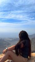 contento asiático mujer turista aumento manos disfruta respiración Fresco aire alto en nublado montañas a frío clima. joven caminante a increíble brumoso antecedentes de montaña paisaje en pie atrás. activo deporte. video