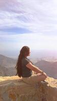 contento asiático mujer turista aumento manos disfruta respiración Fresco aire alto en nublado montañas a frío clima. joven caminante a increíble brumoso antecedentes de montaña paisaje en pie atrás. activo deporte. video