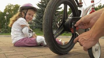 Child bike training wheels. Father teaches his child to ride without training wheels, removing training wheels from the child's bike. video