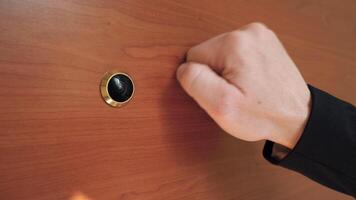 Knocking at the wooden door with peephole. Man asking permission to enter video