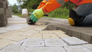 construcción trabajar. constructor tendido pavimentación losas en el calle. masón hace el acera. el constructor hace un pasarela con pavimentación losas o hormigón adoquines. video