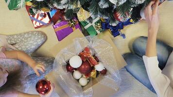 décorer une Noël arbre. mère aide le sien fille à décorer le Noël arbre, vue de Haut video