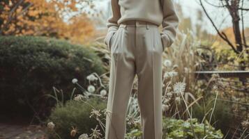 A simple turtleneck sweater paired with highwaisted trousers and loafers showcasing the simplicity and versatility of genderfluid fashion. Background A peaceful garden representin photo