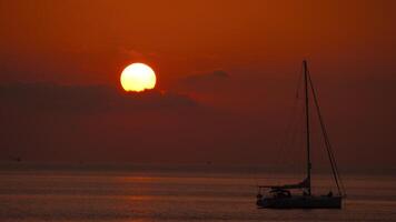 The sun is setting over the ocean with a sailboat in the foreground, creating a scenic view of natures beauty video