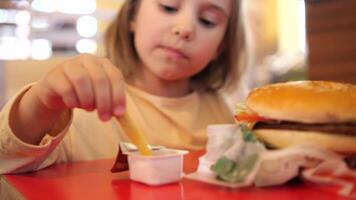 pequeno criança menina fechar-se comendo francês fritas dentro uma velozes Comida restaurante video