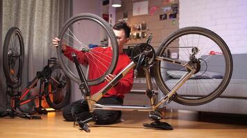 a man in glasses installs a wheel on a bicycle at home video