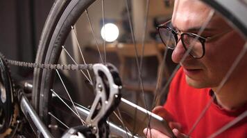 uma homem parece às instruções em uma tábua em quão para consertar uma bicicleta. fechar-se video
