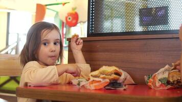 pequeño niño niña de cerca comiendo, rápido alimento, basura alimento, insalubre dieta, papas fritas video