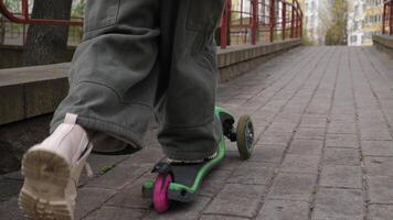 de cerca un pequeño niña con rapidez paseos un scooter video