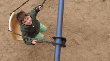 High angle shot of a kid riding on a swing on a rusty chain in slow motion video