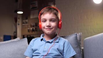 close-up boy in his room puts on orange bright headphones and listens to music video