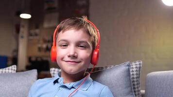 close-up, portrait of a little boy in orange headphones listening to music video