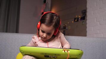 portrait of a little girl in orange headphones plays the electronic piano video