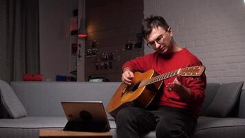 Disappointed man fails playing guitar while watching online tutorial video