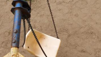 An empty children's swing on a chain sways in the wind. top shooting angle video