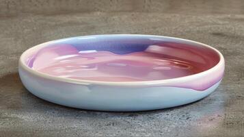 A pottery dish with a layered glaze effect featuring shades of pink purple and blue overlapping each other to create a dreamy cloudlike appearance. photo