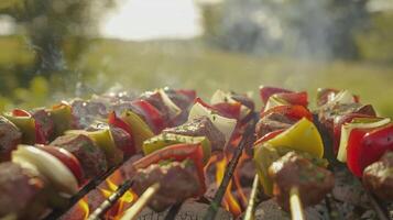 The smell of freshly grass mixes with the scent of sizzling onions and peppers as the grill master cooks up some mouthwatering kebabs photo