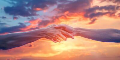 two hands reach out to each other against the backdrop of sunset photo