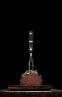 juicy steak on a fork with on a black background photo