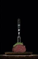 juicy steak on a fork with on a black background photo