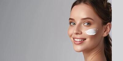 young woman with cosmetic cream on her face skin care photo