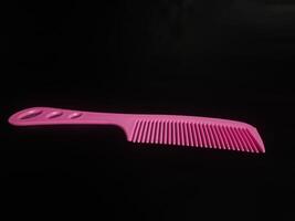 photography of a pink comb on a black background photo