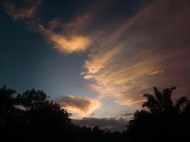 fotografía de un hermosa noche cielo con naranja luz de sol foto