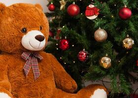 Teddy bear near christmas tree with gifts photo