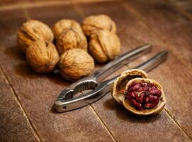 Red Danube Walnuts with silver nutcracker on wooden background photo