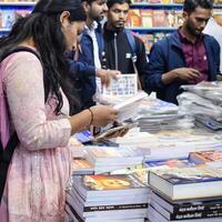 Delhi, India, February 17 2024 - Various age group people reading variety of Books on shelf inside a book-stall at Delhi International Book Fair, Books in Annual Book Fair at Bharat Mandapam complex photo