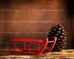 Wooden red sled with brown pine cone photo