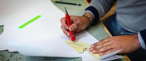 Shoe designer working with paper models for leather cutting. photo