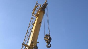 Mobile crane with hook and straps is raising work platform, basket. video