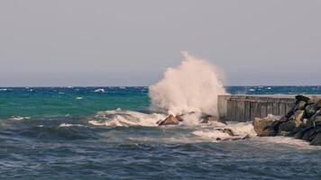 Massive wave crashing against rock formation in ocean video