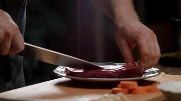 kok handen besnoeiing een ader van een stuk van rauw vlees gebruik makend van een mes. venatie van vlees. hij ook scheiden kraakbeen en pezen van de vlees. dichtbij omhoog. langzaam beweging. 4k. video