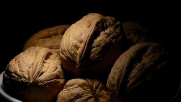 Walnuts in a white bowl gyrating on black background with a cenital light video