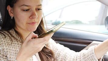 ung kvinna sändning en röst meddelande med mobil telefon inuti de bil. hög kvalitet 4k antal fot video