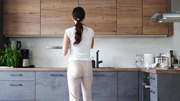 Young woman dancing and singing while preparing soup in her home kitchen and using various kitchen utensils. High quality 4k footage video