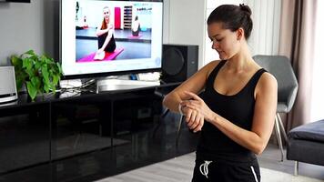 Young woman looking at fitness tracker displaying heart rate, steps count and burnt calories. Smart watch on female hand, point of view, concept of staying fit at home. High quality 4k footage video