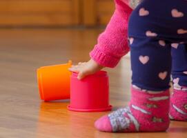 Toddler baby girl plays with colored cups photo