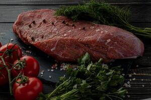 Raw beef steak with spices on a dark slate, stoneselective focus photo