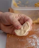 Woman hands are making a damp dumpling. On the wooden counter photo