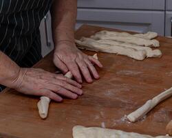 Female hands knead the dough on a wooden table photo