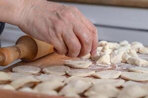 woman hands are making a damp dumpling. On the wooden counter photo