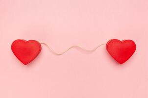 Pair of red hearts connected with a string of twine photo