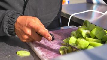 hand in gloves cutting kiwi on a chopping board at street video